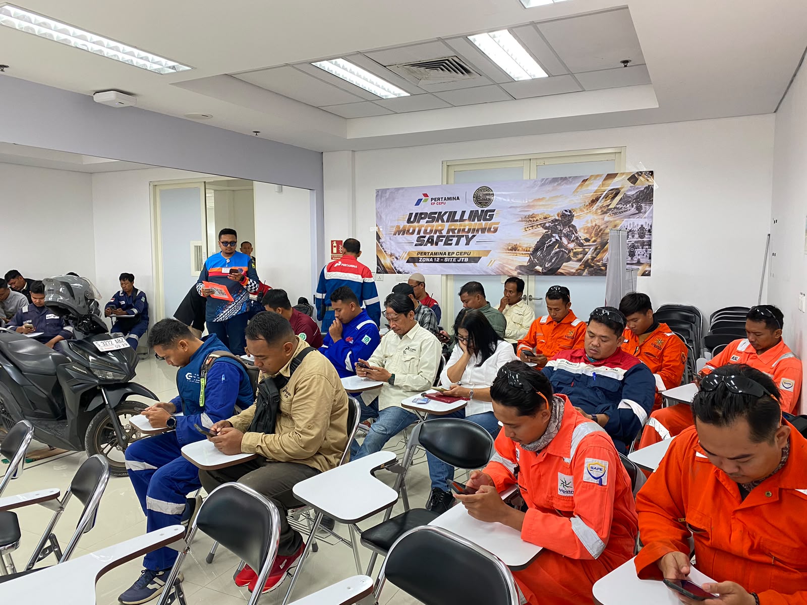 Peserta mengikuti pemaparan materi Defensive Riding Awareness di ruang kelas dengan sepeda motor sebagai sarana demonstrasi